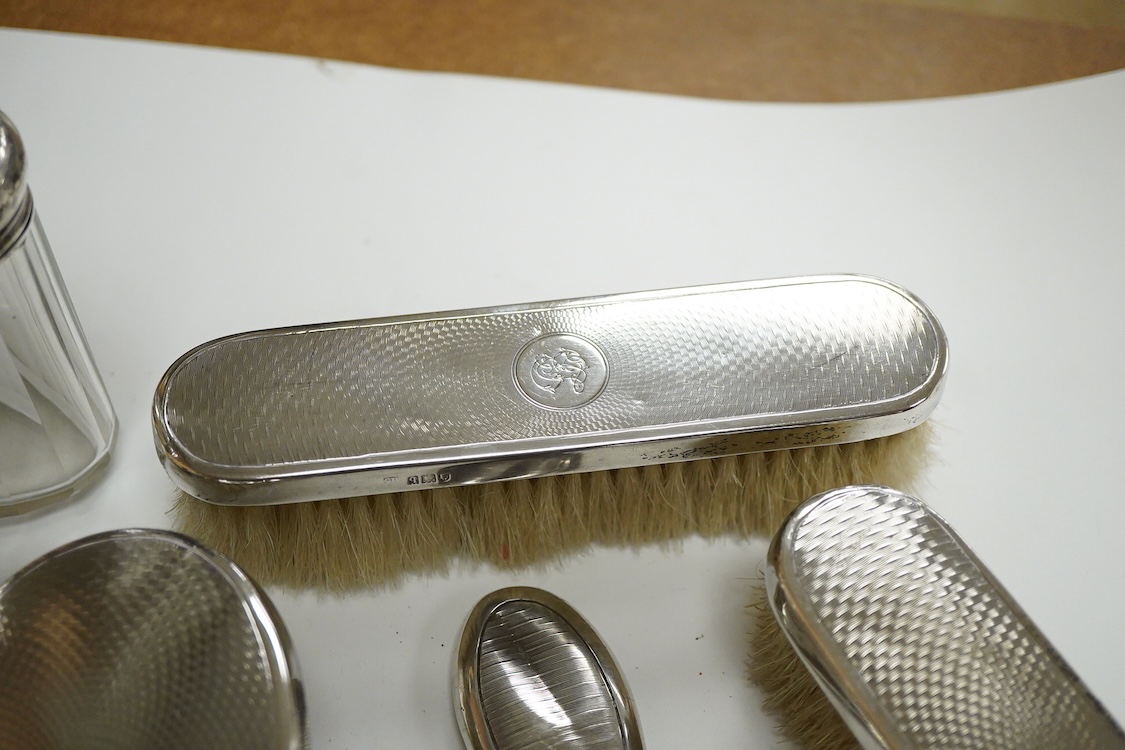 A George V seven piece silver mounted toilet set by Charles Henry Dumenil, comprising a hand mirror, four brushes, a glass toilet jar and button hook, London, 1911/12 & 18, together with one other silver mounted toilet j